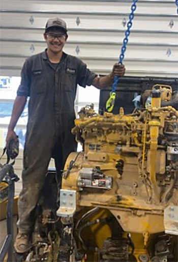 Dante Otsuka with a diesel engine on a hoist